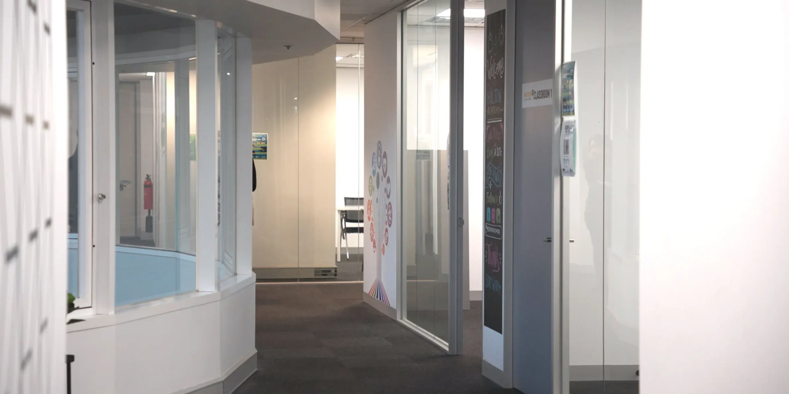 A well lit hallway showing multiple classrooms and study places on campus at Laurus Higher Education.