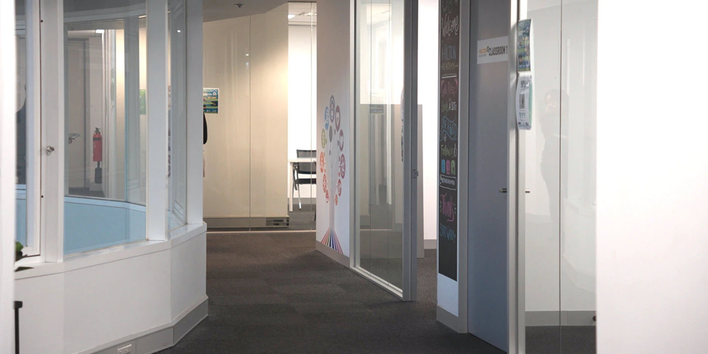 A well lit hallway showing multiple classrooms and study places on campus at Laurus Higher Education.